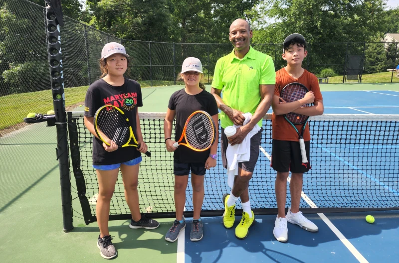 A man and three kids with tennis rackets
